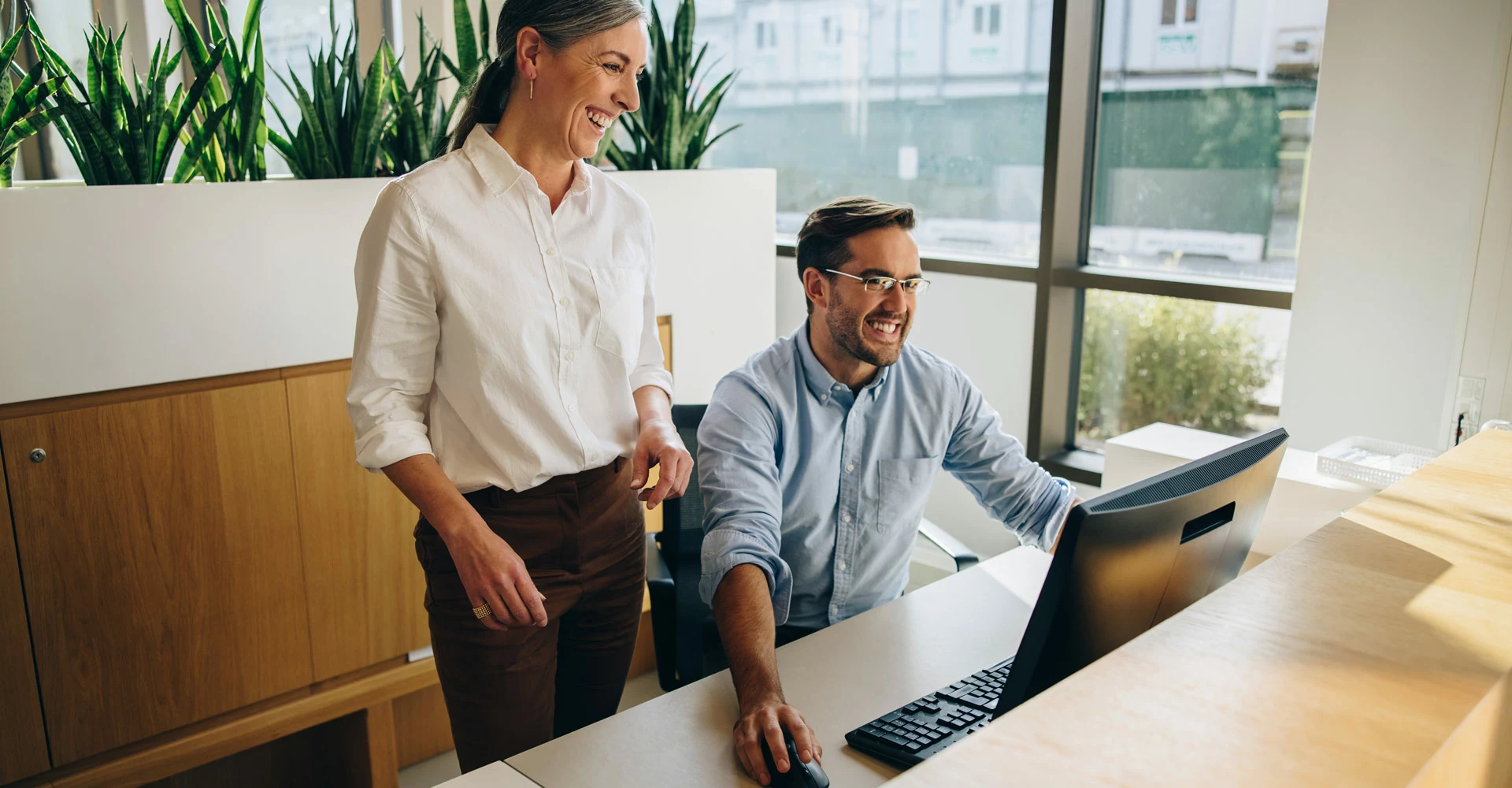 Ein Mann und eine Frau schauen auf einen Computerbildschirm