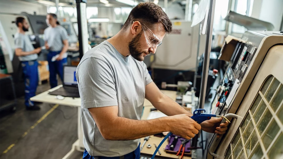 QM-Mitarbeiter an einer Maschine in der Produktionshalle