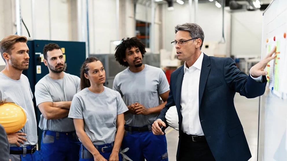 Teamleiter instruiert sein Team in der Produktionshalle