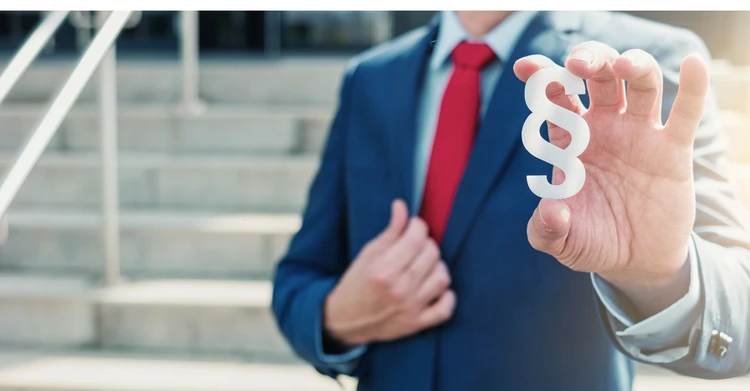 Mann hält Paragraphen-Symbol in der Hand